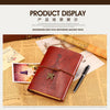 A brown leather journal notebook with a decorative clasp rests on aged paper and a quill pen.