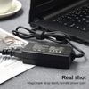 A black universal laptop power adapter with a magic tape strap is shown next to an open laptop.