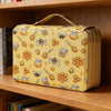 A yellow pencil case with honeycomb and bee patterns is displayed on a wooden shelf.