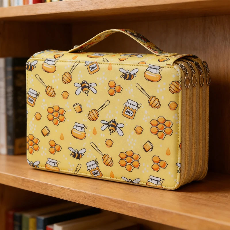 A yellow pencil case with honeycomb and bee patterns is displayed on a wooden shelf.
