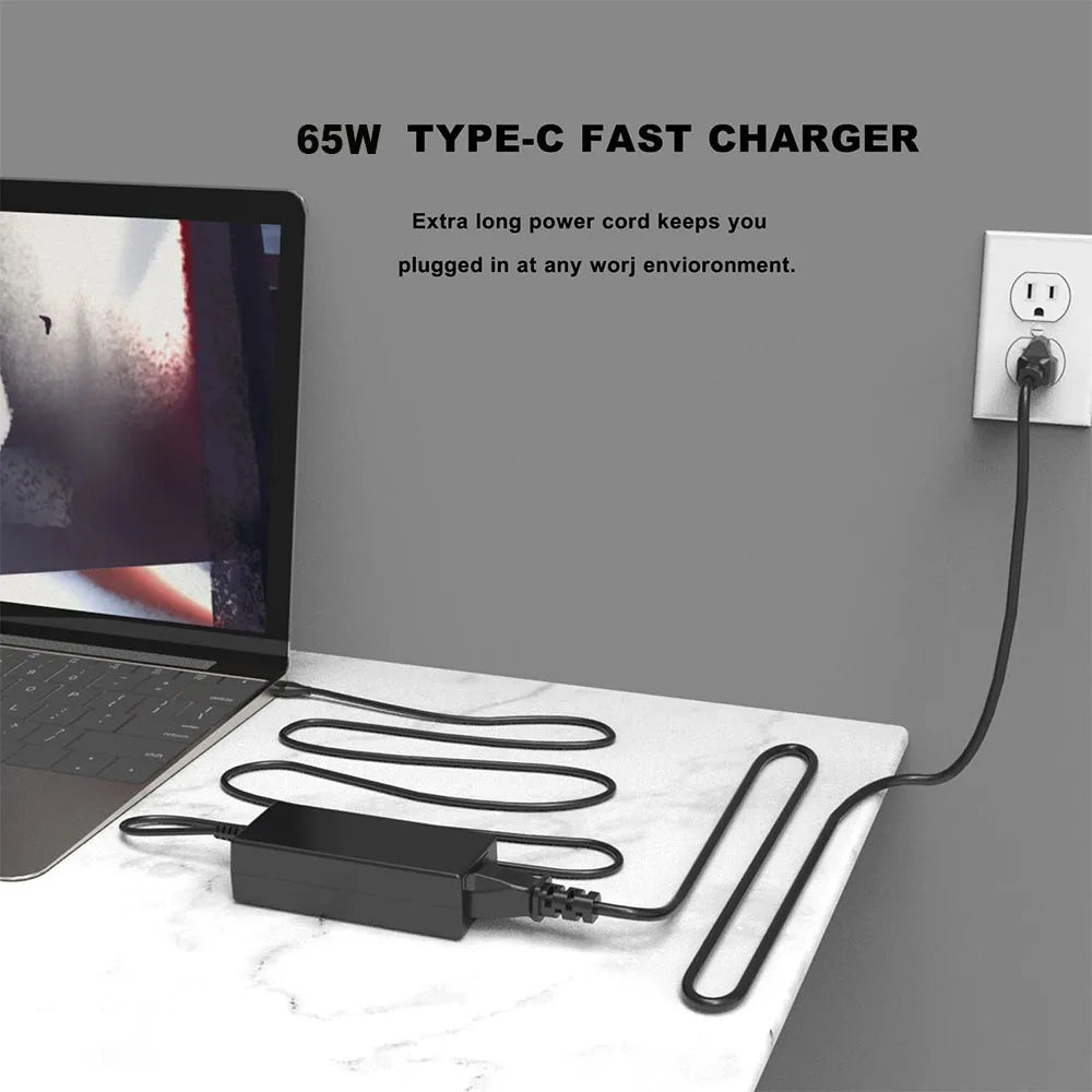 A black 65W Type-C fast charger power cord plugged into a laptop and lying on a white surface.
