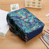 A dark blue pencil case with a tropical leaf pattern and multiple compartments resting on a wooden table.
