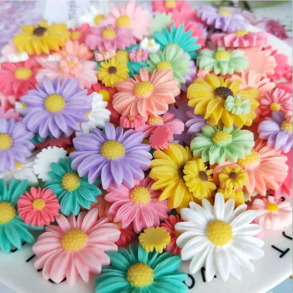 A colorful arrangement of pink, yellow, purple, and green sunflower flatback resin cabochons for crafts.