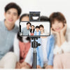 A close-up of an adjustable phone and tablet tripod mount with a camera attached, positioned in front of several people.