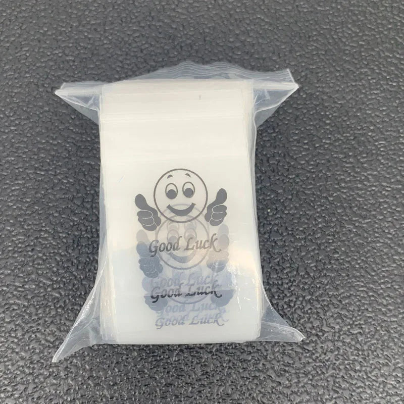 A clear plastic ziplock jewelry bag containing a small charm with the text Good Luck