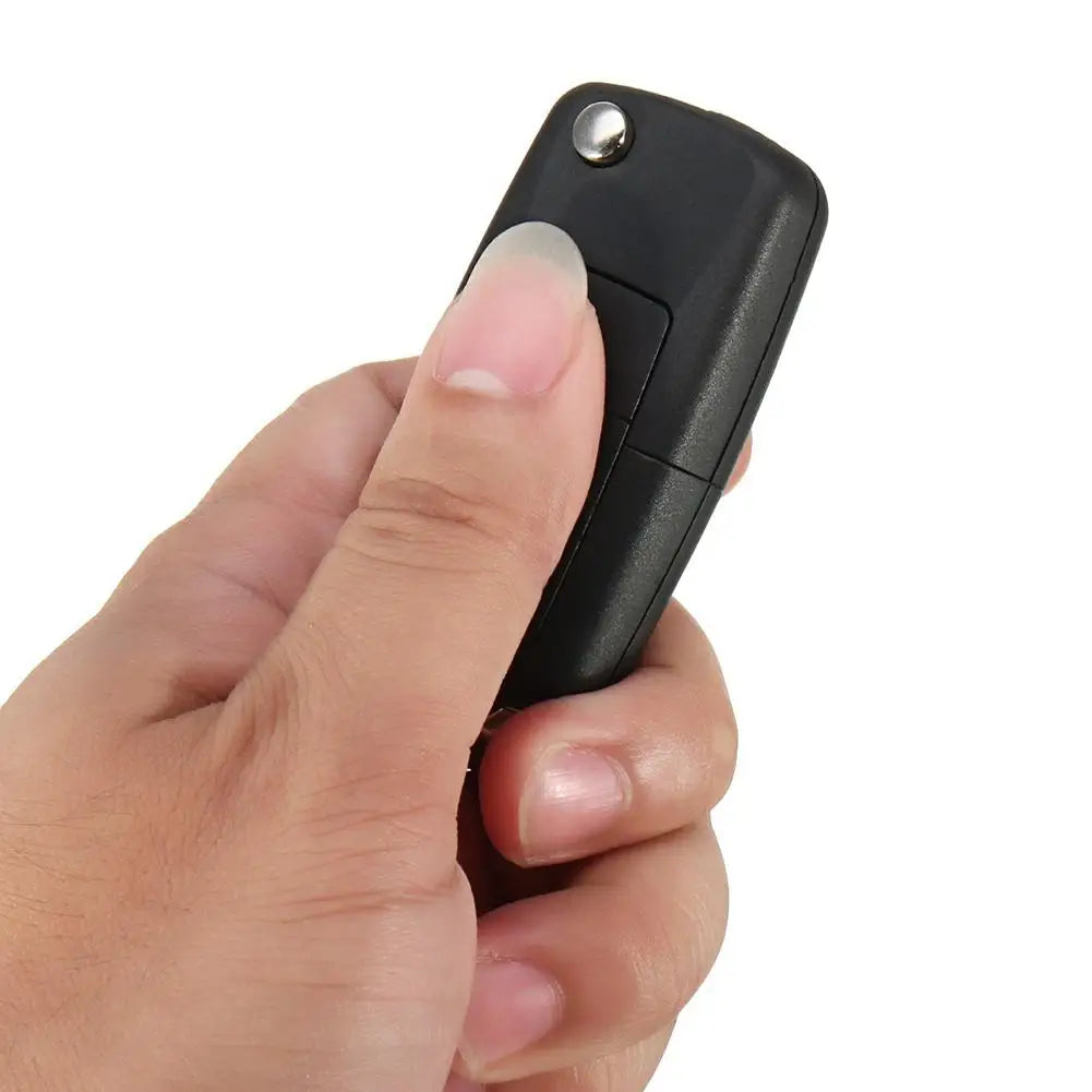 A hand is holding a black realistic fake car key hidden safe with a secret compartment.