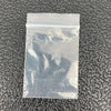 A clear plastic ziplock jewelry bag lying on a dark textured surface.