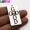 A white rectangle charm pendant engraved with the text God Is Good is held in a hand.
