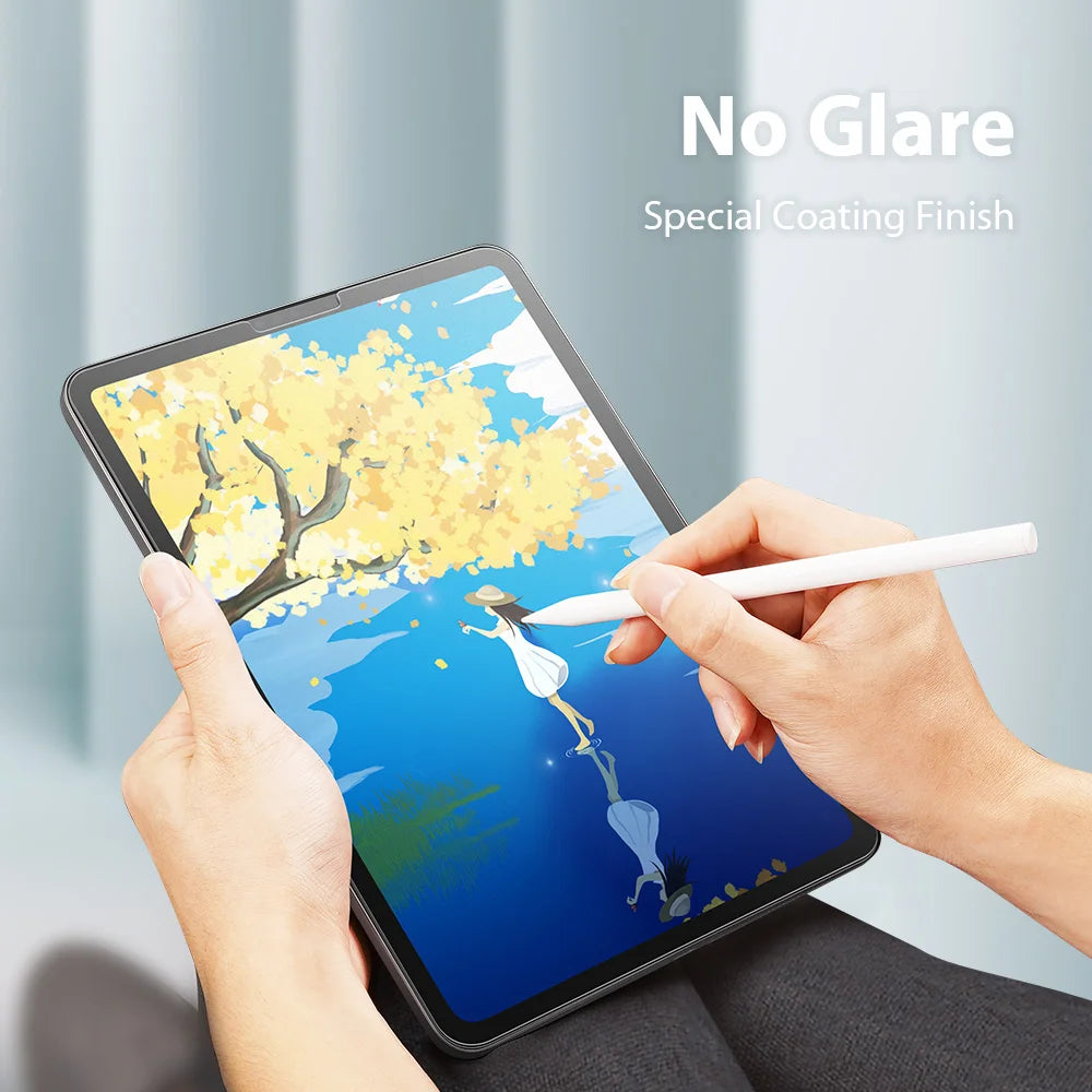 Hands hold an iPad displaying a yellow tree against a blue sky, featuring a No Glare Special Coating Finish screen protector.