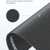 Close-up view of a black non-slip rubber mouse pad with a textured surface attached to the desktop.