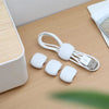 White silicone cable organizer clips and a USB connector lying on a wooden surface.