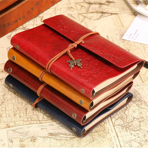 A stack of vintage red and brown PU leather A6 journal notebooks tied with leather thongs on a map background.