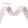 A pink bristleglass ribbon or hair tie shown in a draped, wavy shape.