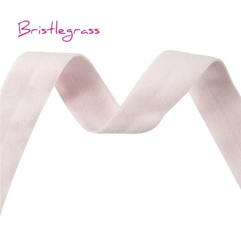 A pink bristleglass ribbon or hair tie shown in a draped, wavy shape.
