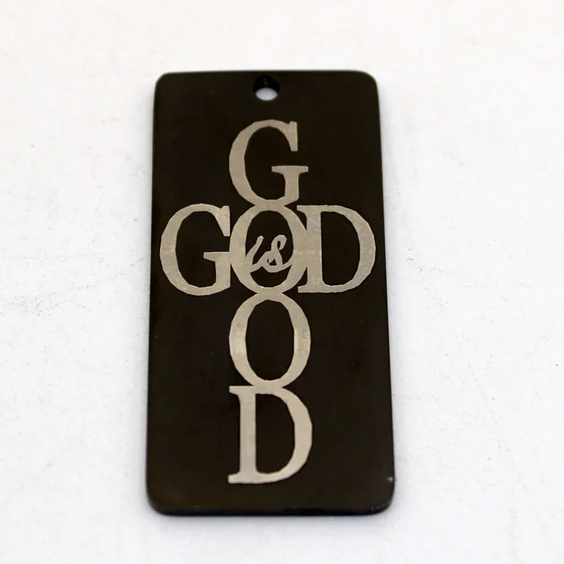 A dark rectangle stainless steel charm pendant engraved with the words GOD IS GOOD