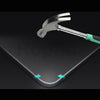 A silver and green tempered glass screen protector is shown resting on a dark surface.