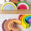 Un conjunto de bloques de construcción en forma de arcoíris de madera en varios colores pastel y vibrantes, dispuestos en un 