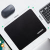 A black non-slip rubber mouse pad is shown next to a computer mouse and a laptop.
