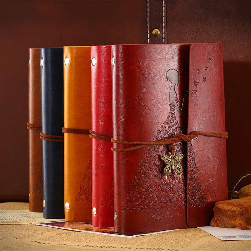 A set of five vintage red and orange PU leather A6 journal notebooks standing upright on a wooden surface.