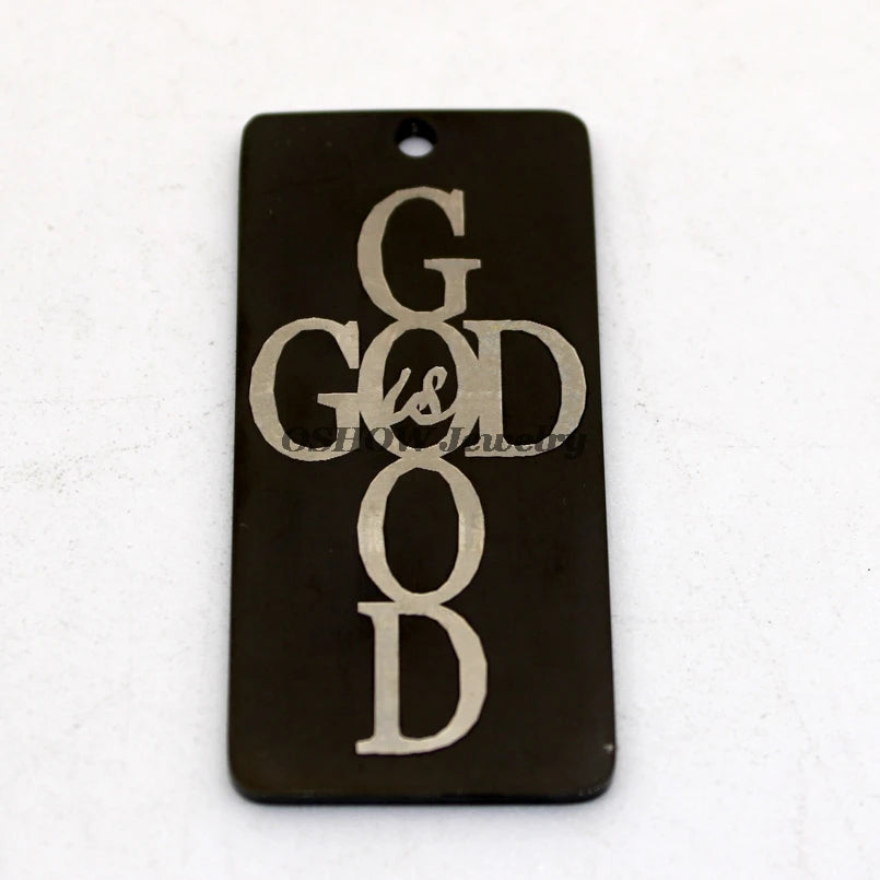 A black rectangle charm pendant with the words GOD IS GOOD engraved in silver script.