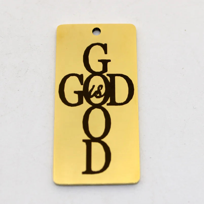 A gold-colored stainless steel rectangle charm pendant engraved with the text God Is Good.