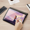 A hand is writing on a tablet displaying a sunset landscape, next to a smartphone and a pen.