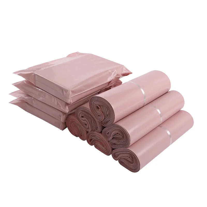 A stack of pink waterproof self-seal poly mail bags in various sizes and rolls.