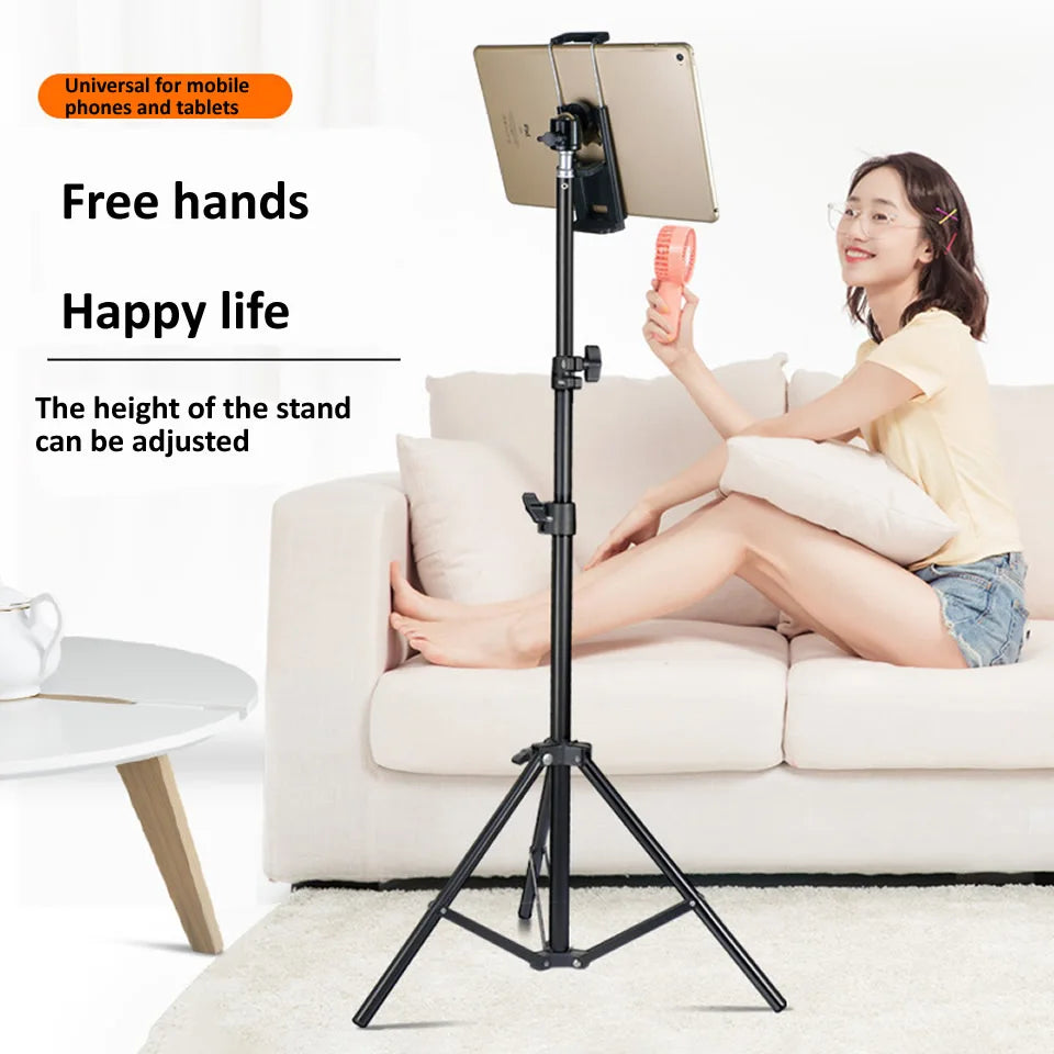 A woman is using an adjustable tripod stand to hold a tablet, demonstrating its versatility for mobile devices.