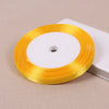 A roll of gold yellow satin ribbon with a white center core placed on a light background.