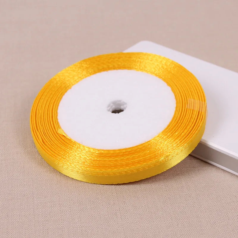 A roll of gold yellow satin ribbon with a white center core placed on a light background.