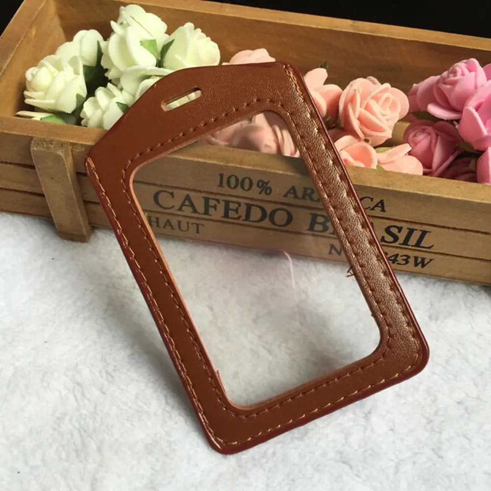 A brown PU leather ID card holder with a cutout for a lanyard is displayed in a wooden box with pink and white roses.
