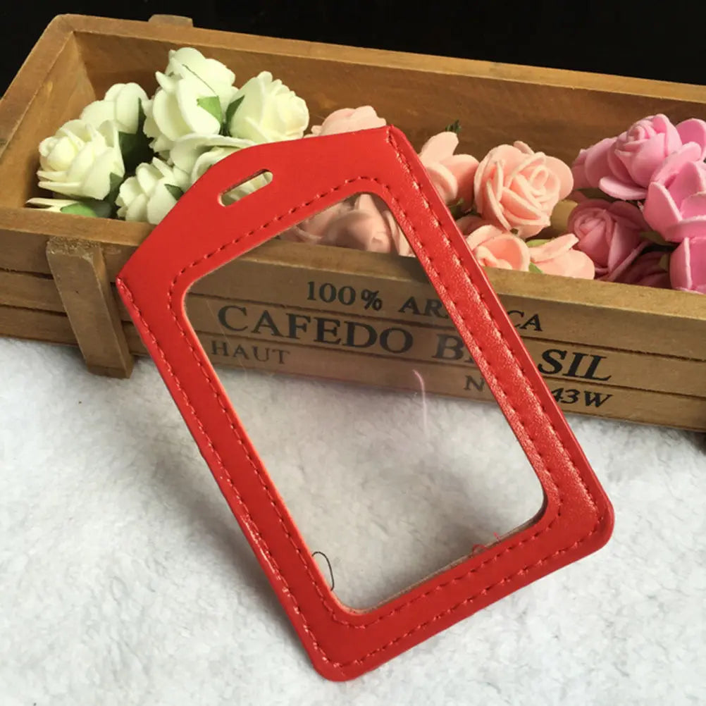 Red PU leather ID card holder with a cutout shape resting on a wooden tray filled with pink and white roses.