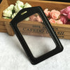Black PU leather ID card holder with a rectangular shape resting on a wooden box surrounded by pink and white roses.