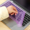 Eine Hand legt eine lila Silikon-Keyboard-Schutzfolie auf eine Laptop-Tastatur.