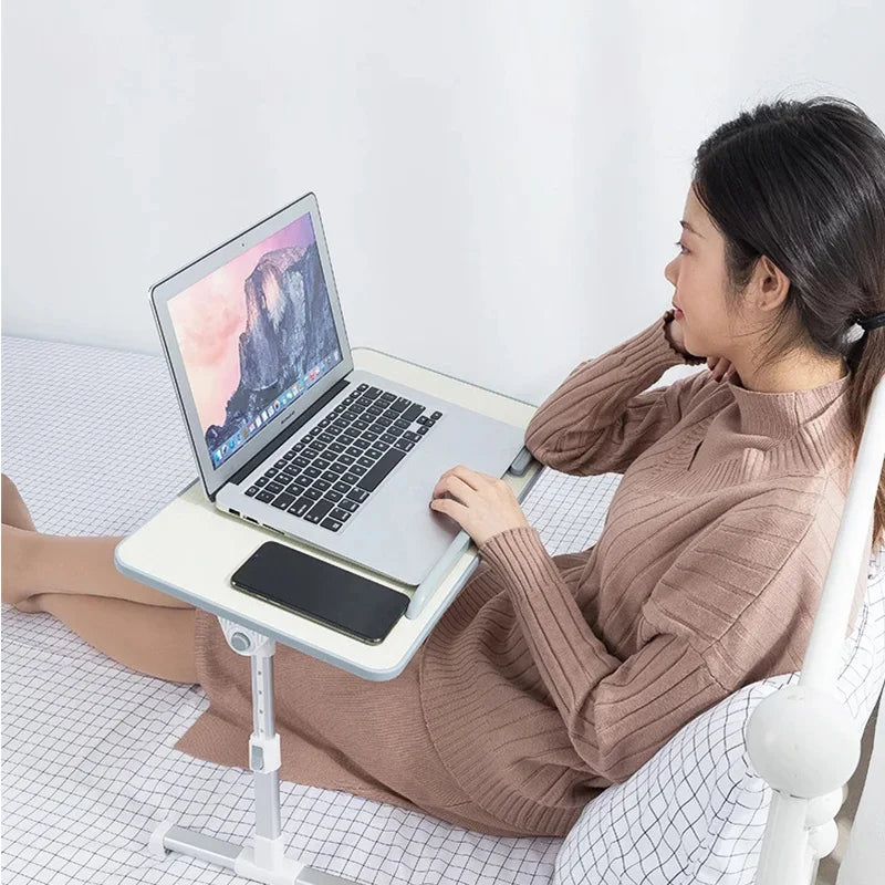A woman is using a portable adjustable laptop desk stand to position her laptop for viewing.