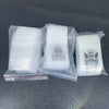 Several clear plastic ziplock jewelry bags containing small white items with smiley faces.