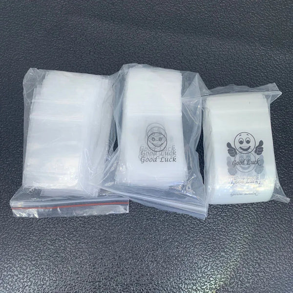 Several clear plastic ziplock jewelry bags containing small white items with smiley faces.