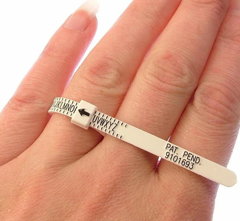 Eine Hand hält ein Präzisionsmessband und einen Ringgrößen-Sizer mit Markierungen und Identifikationsnummern.