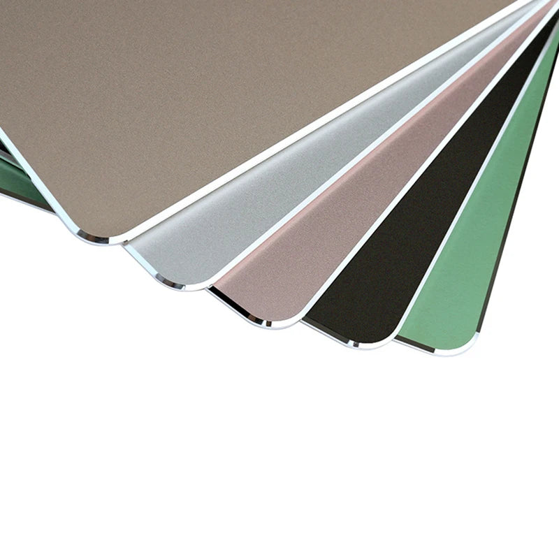 A stack of premium aluminum and PU leather mouse pads in various neutral and muted colors.