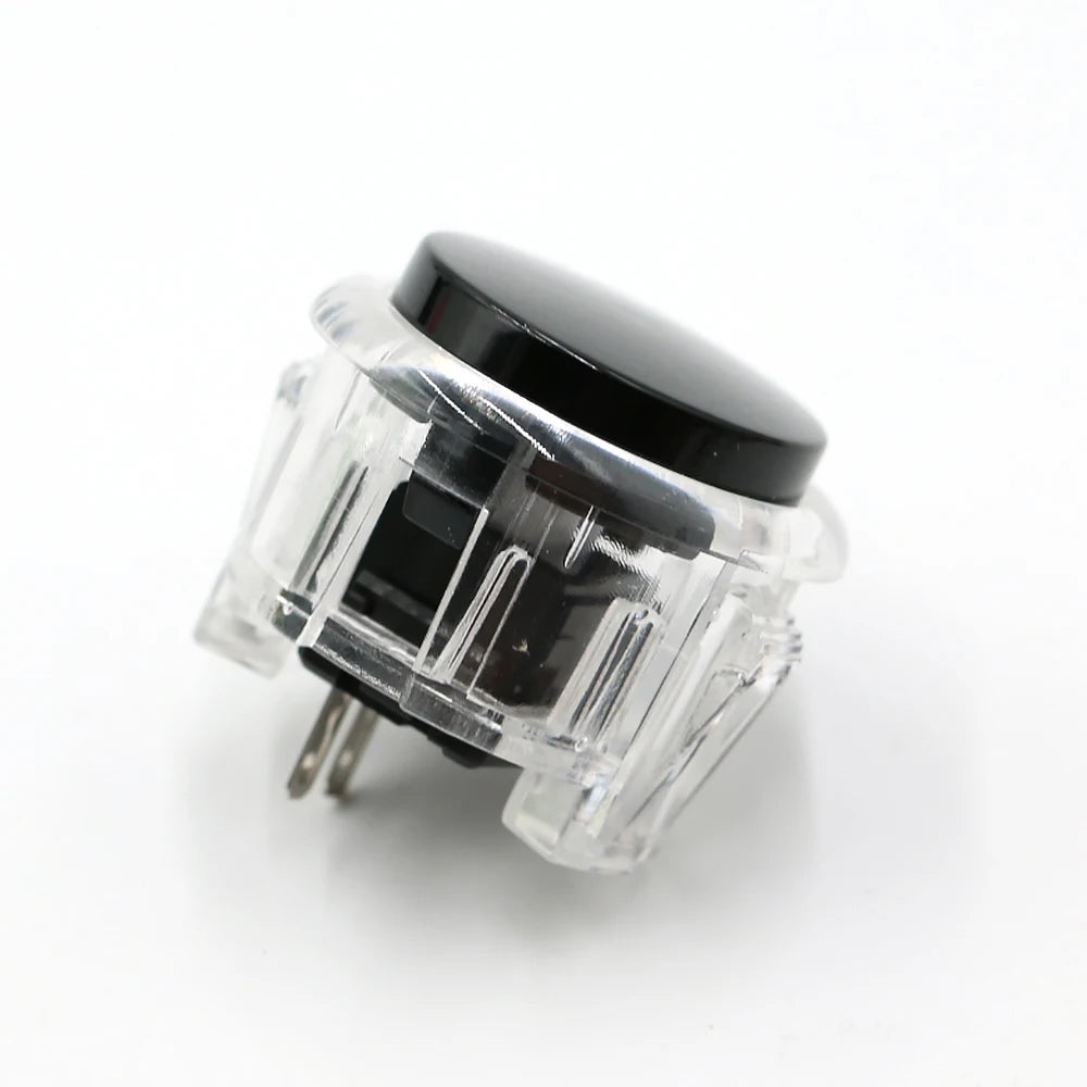 A clear plastic arcade push button game switch with a black dome top and metal pins.