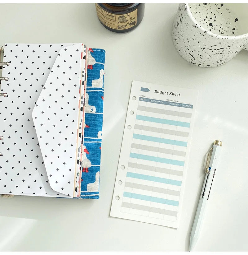 A set of six-color budget planner cards with various designs and a budget sheet are displayed on a white surface.