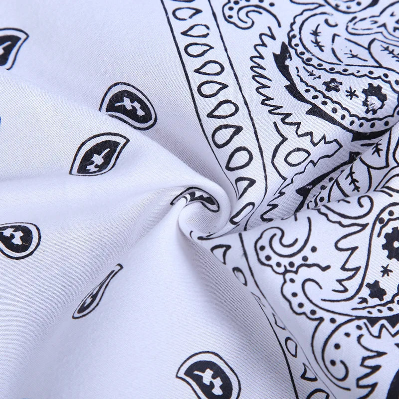 White fabric with a black paisley print folded to show the pattern detail.