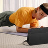 A person is using a portable laptop monitor while doing an exercise on a yoga mat.