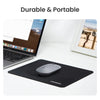 A black ergonomic mouse pad is shown on a white desk next to a laptop and a framed photo.