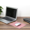 A silver laptop is shown next to a pink mouse pad and a black mouse on a wooden desk.