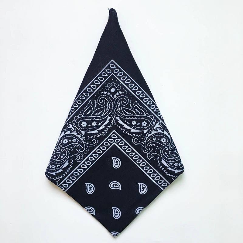 A black bandana square scarf with white paisley print folded into a triangle shape.