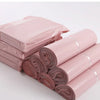 Pink waterproof self-seal poly mail bags stacked and rolled for sale