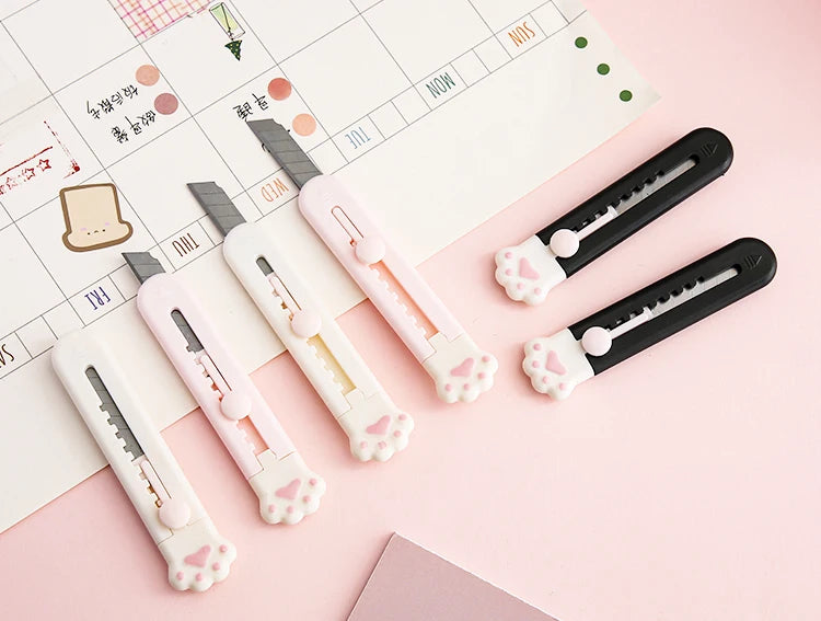 A collection of pink and black portable pet claw tools or knives laid on a calendar page.