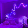 Una luz de neón morada con forma de onda se muestra en la pared sobre una cama.