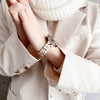 A close-up of a wrist wearing a resin beaded watch band with a three-bead design on a light blazer sleeve.